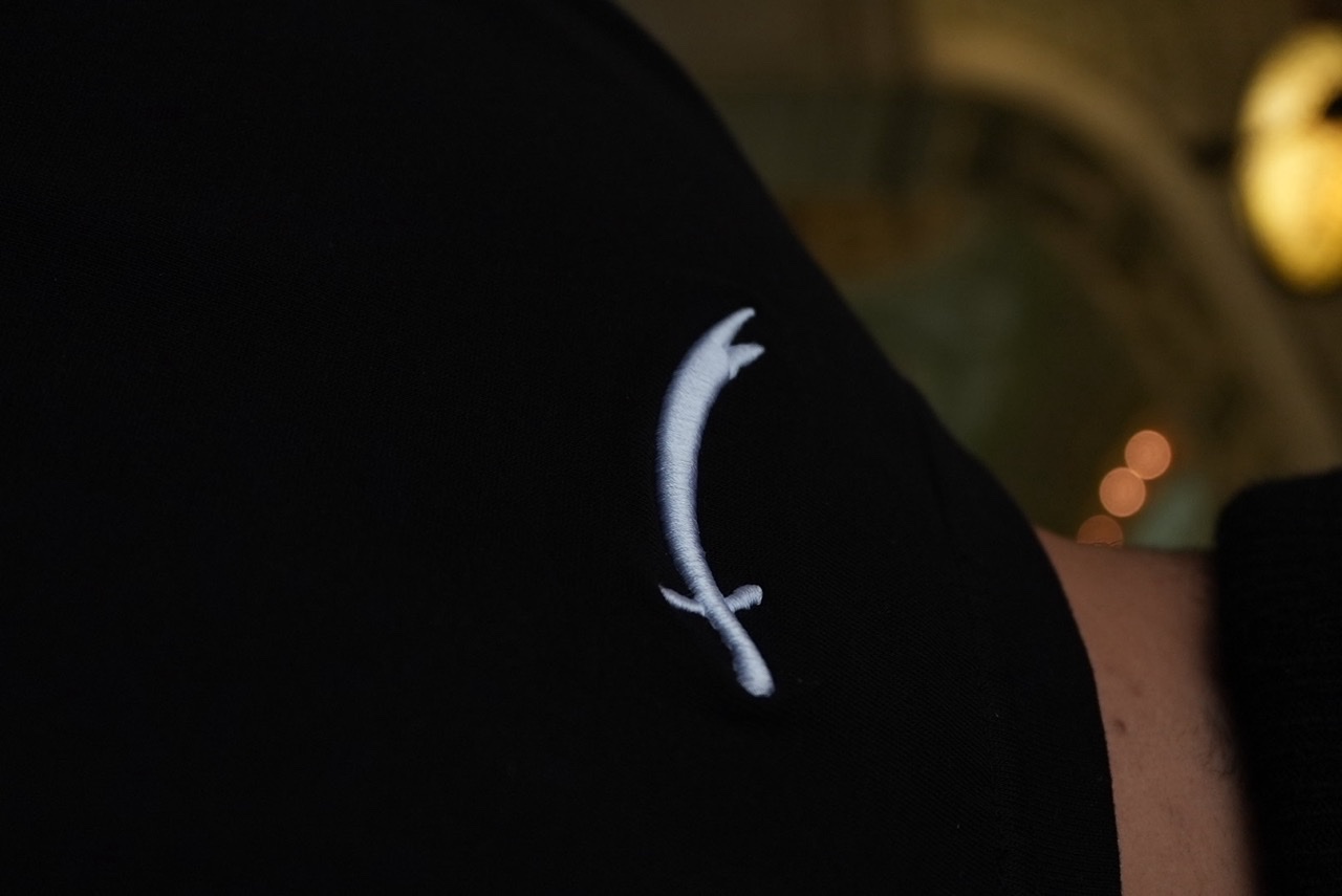 Original 40 Nights tee shoulder photograph showing the small white curved-sword mark